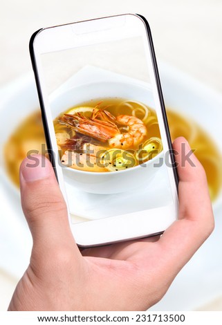 Hands taking photo salmon soup, shrimp with smartphone