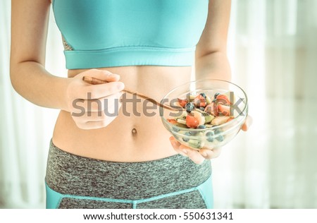 Young woman eating a healthy fruit salad after workout. Fitness and healthy lifestyle concept.