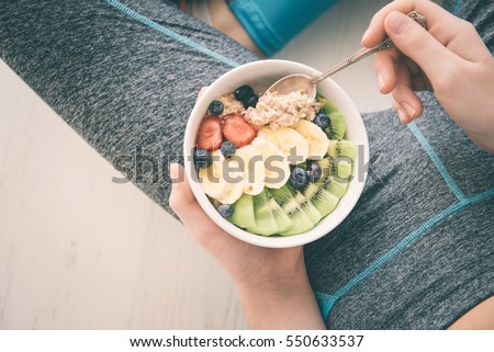 Young woman is resting and eating a healthy oatmeal after a workout. Fitness and healthy lifestyle concept.