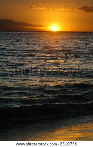 Swimmer with boogie board in ocean water at sunset