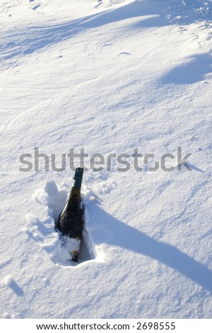 Vertical view of bottle of sparkling wine chilling in snow bank
