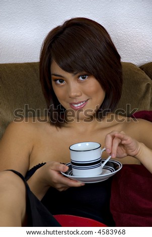 sitting young beautiful asian woman with brunette hair and brown eyes smiling and holding cup