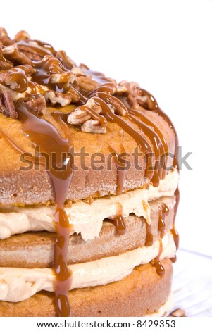 sweet pumpkin cake dessert with cream filling and pecans on top drizzled with caramel topping on clear plate