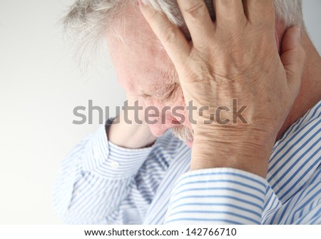 stressed older man holds his head in both hands