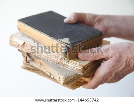 a man holds several old, damaged books