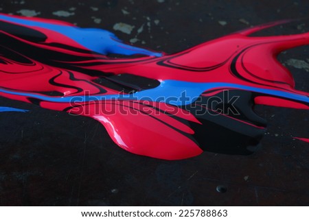 Blue, red and black paints swirled over a dark metallic background