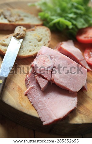 Slices of ham, lettuce, tomato, bread and a deli mustard