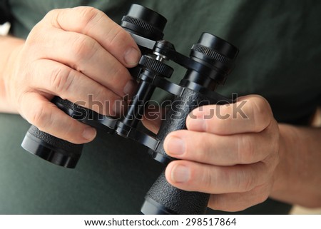 A senior man holding a pair of old binoculars