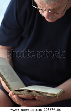 Older man reading a book, leaving a dark area for text