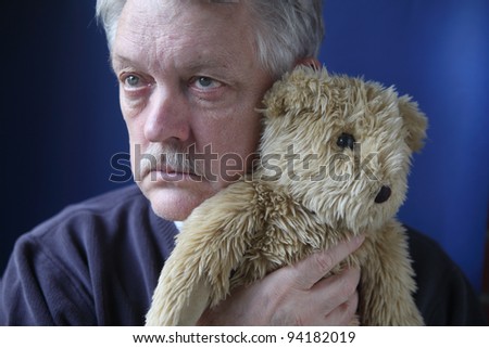 an older man holds a generic stuffed animal close to his face