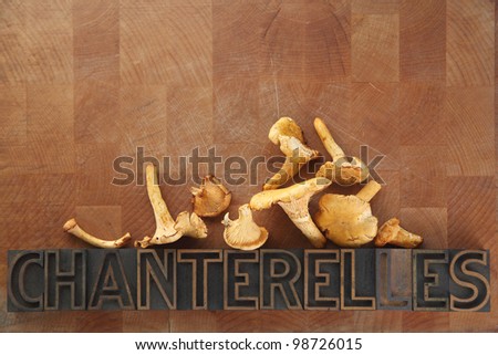 fresh chanterelles with the word in old wood type on an old cutting board