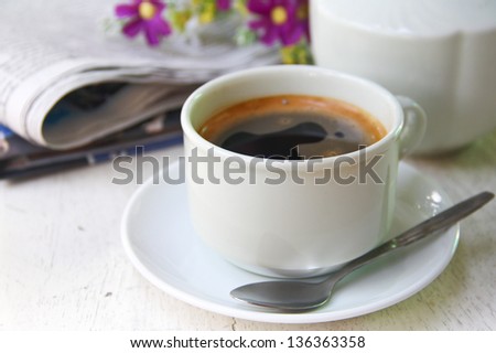 a cup of coffee and newspaper on table