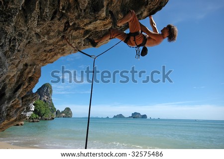 Adult climbing hard overhanging wall in Krabi, Thailand.