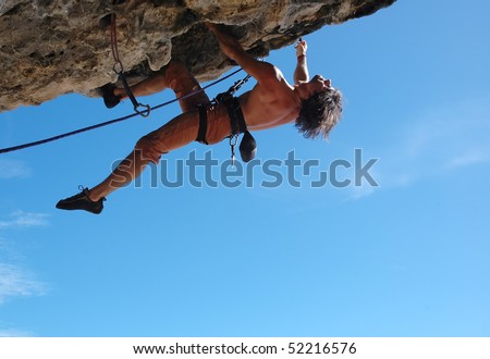 Adult climbing hard overhanging rock.