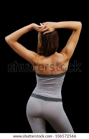 Young woman is bending her attractive body and putting her hands behind her head. She is wearing a polka-dot body suit.