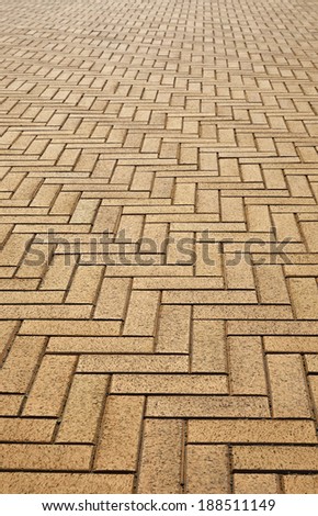 Herringbone structure of the paver flooring is photographed closely with diminishing perspective.