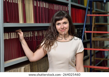 A young cheerful woman is working the old scientific journals in the stillage.