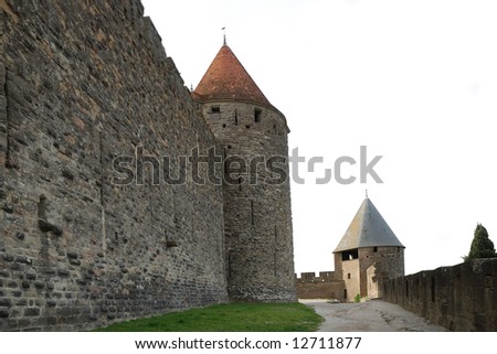 Inner old defense wall with conic towers of Carcasson castle in sunlight and road along, France