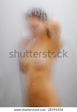 stock photo Nude girl in shower through glass with drops of water