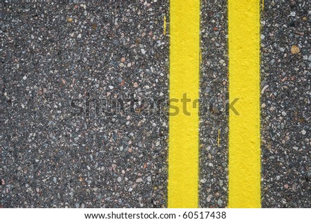 Two yellow lines are painted on asphalt surfacing. The highway is photographed closely. There is copy space.