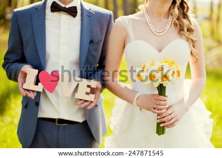 bride and groom holding bouquet and wooden word love