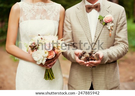 bride and groom holding bouquet and pinecones