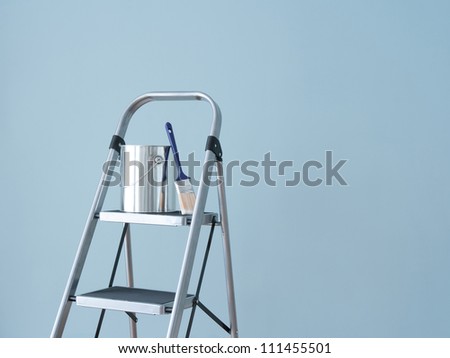 Preparing to paint the wall. Painting tools on a metal ladder.