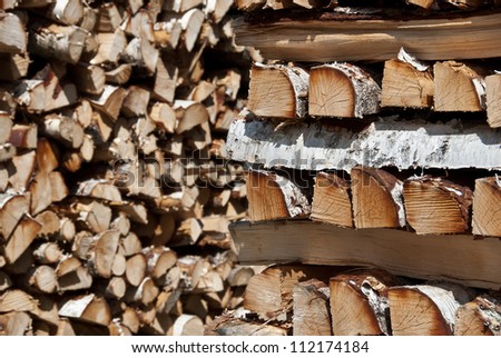 Chopped birch wood logs stacked in big piles.
