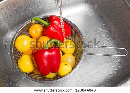 Washing colorful fruits and vegetables in the kitchen sink.