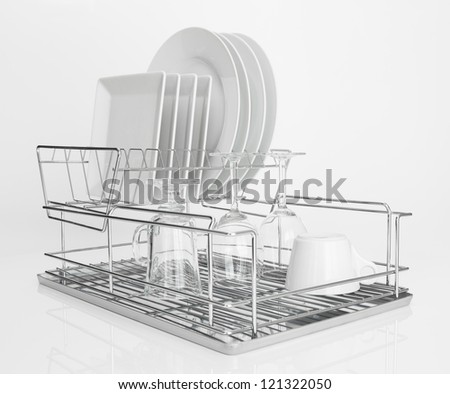 White dishes and wine glasses drying on a metal dish rack.
