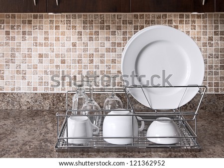 Dish Rack With White Plates And Cups On Kitchen Countertop.