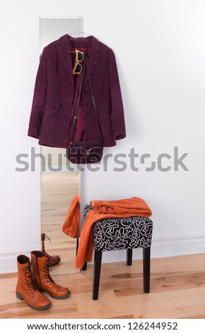 Purple jacket hanging on a mirror. Orange boots and pants, room reflection.