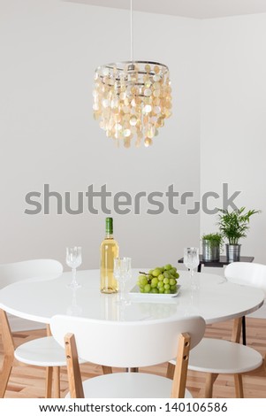 Room With Decorative Chandelier, White Round Table And Plants.