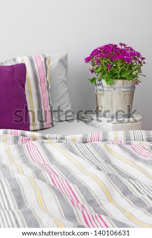 Modern bedroom decorated with purple flowers and cushions.