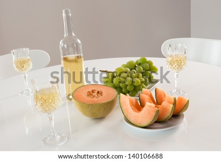 White wine with melon and grapes on a round table.