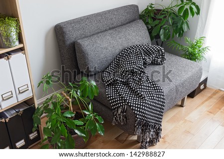 Living room with bright green plants, bookshelf and gray armchair.