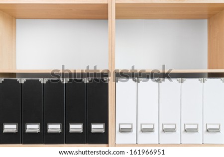 Bookcase with black and white folders and two empty shelves.