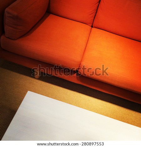 Bright orange sofa and coffee table. Living room detail.