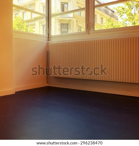 Empty room with city view, in warm light.
