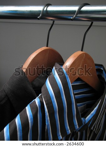 Two stylish shirts on wooden hangers