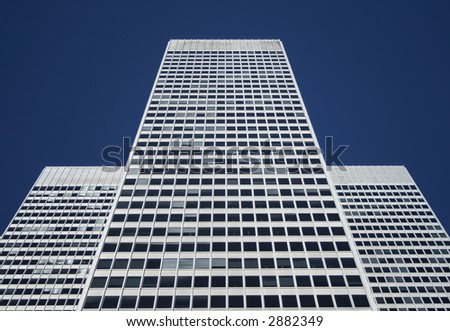 Three-part symmetrical white office building against the blue sky.
