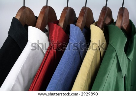 Man\'s wear: choice of colorful shirts on wooden hangers.