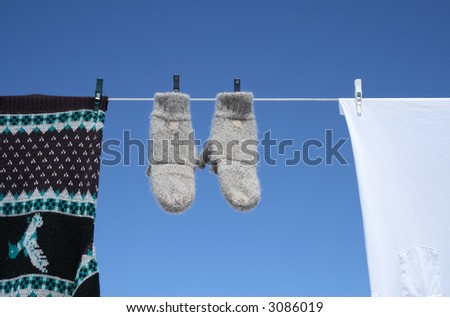 Spring laundry – mittens, sweater and t-shirt hanging to dry on a clothes-line.