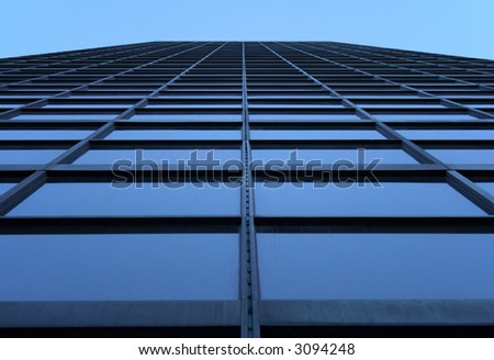 Glass-windowed skyscraper reaching the sky. View directly from below.