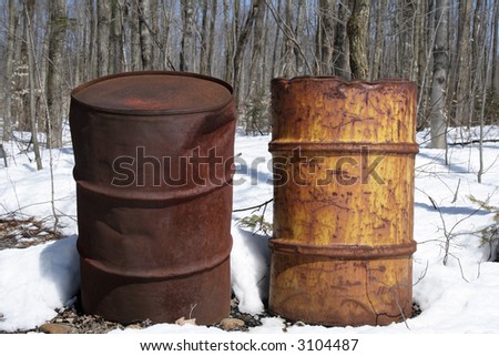 Two rusty iron barrels left in the forest.