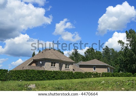 New house surrounded by a hedge, in a rich suburban neighborhood.