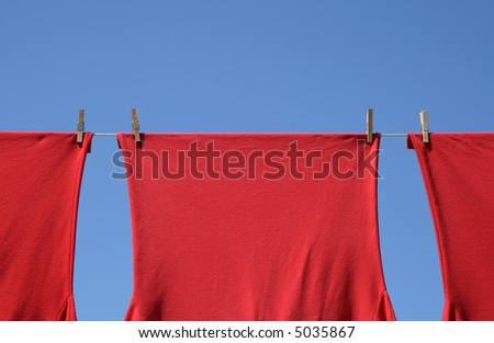 Red corporate t-shirts which hang to dry on a clothes-line.