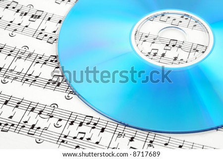Blue CD or DVD on sheet music. Digital music concept.