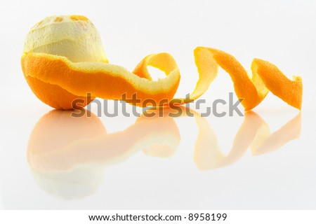 Orange with peeled skin reflecting in glass surface.
