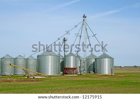 Grain silos on a farm in green spring field.